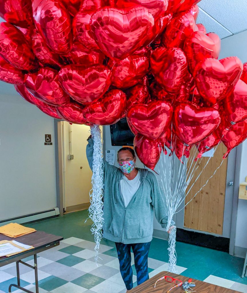 A photograph of an employee delivering heart shaped balloons to residents at Blake Street Towers
